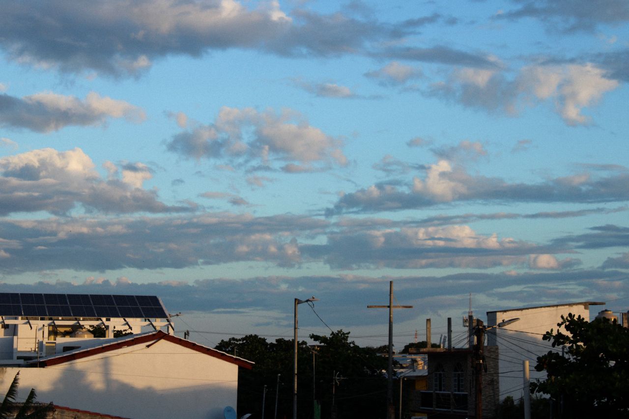 The Art of Drawing Readers In: Your attractive post title goes here A scenic view of rooftops with solar panels under a cloudy blue sky during the day.