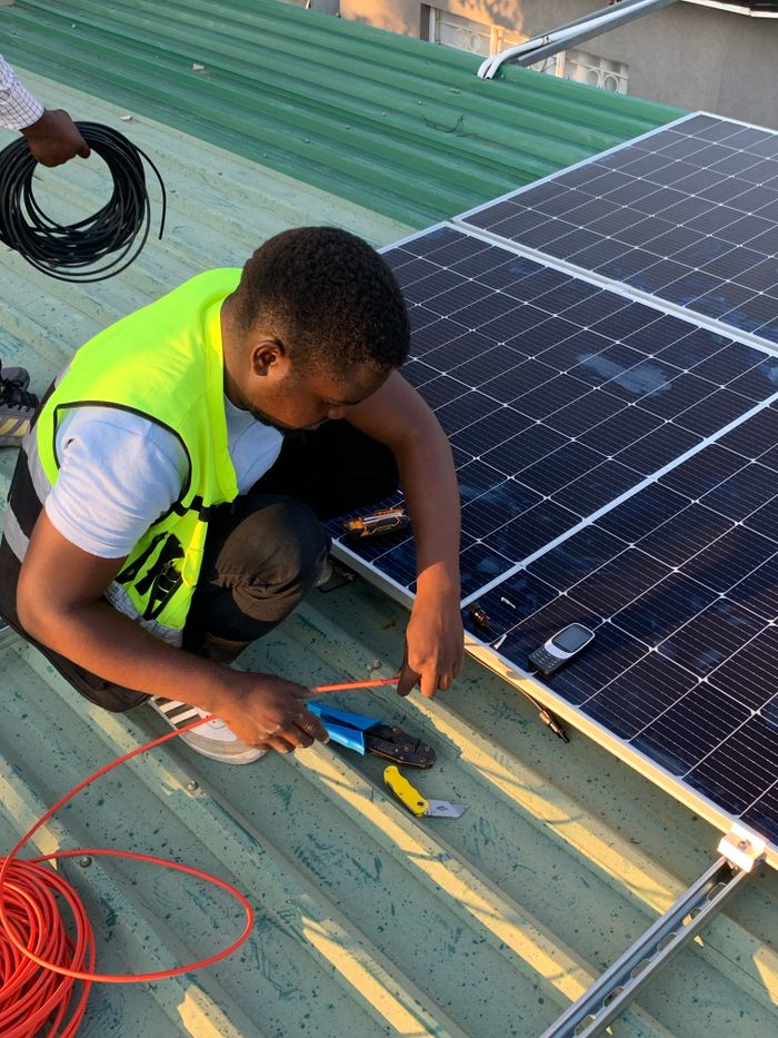 our-values Technician working on solar panel installation with cables and tools on a sunny day.